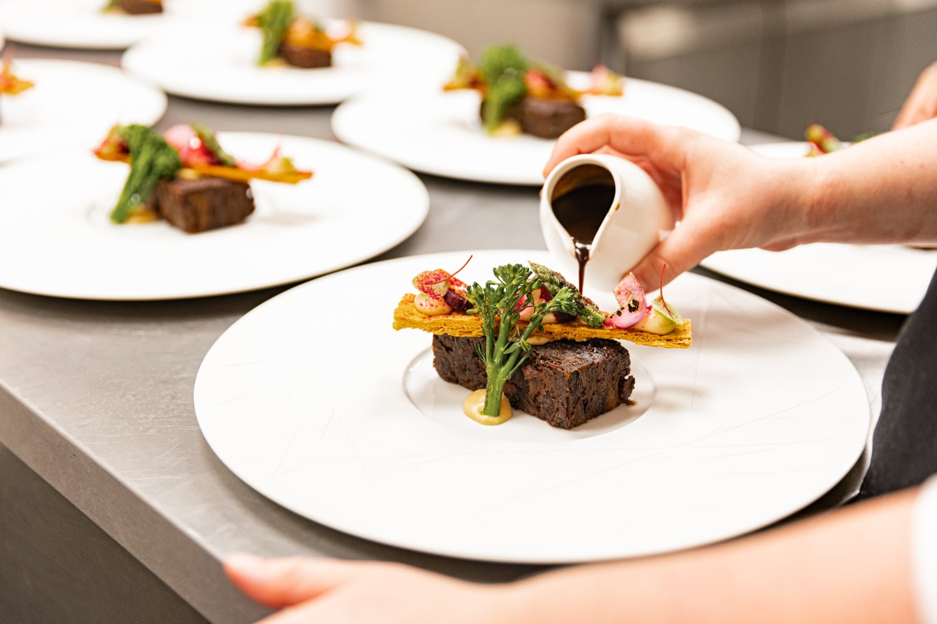 Chef giet saus over short rib met broccolini en bladerdeeg — foto Marije de Boer